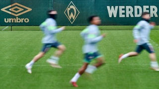 Drei Werder-Spieler sprinten über den Trainingsplatz.