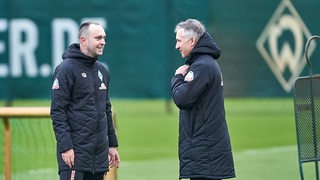 Ole Werner und Frank Baumann unterhalten sich auf den Trainingsplatz.