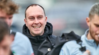 Ole Werner lacht inmitten seiner Spieler auf dem Weg zum Trainingsplatz.