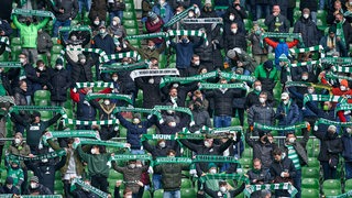Im Weser-Stadion halten zahlreiche Werder-Fans ihr Schals hoch.
