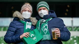 Zwei Fans stehen im Weser-Stadion und lächeln.