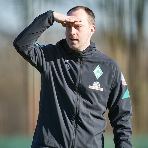 Werder-Trainer Ole Werner legt seine Hand über die Augenpartien und blickt in die Ferne.