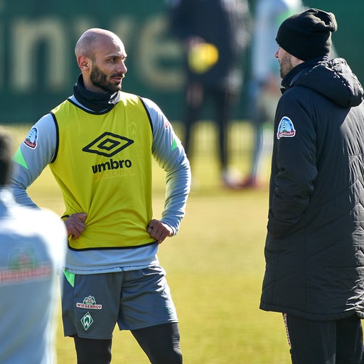 Werder-Kapitän Ömer Toprak im gelben Leibchen im Gespräch mit Trainer Ole Werner am Rande des Trainings.