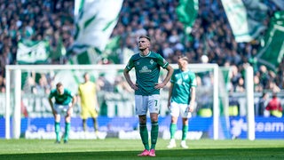 Werder-Spieler Marvin Ducksch steht mit den Händen in den Hüften auf dem Rasen.