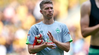 Werder-Profi Mitchell Weiser applaudiert nachdenklich nach dem Spiel auf dem Platz.