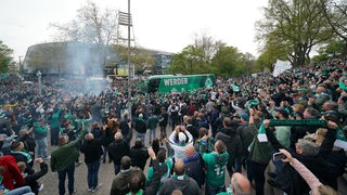 Tausende Werder-Fans stehen Spalier vor dem Weserstadion und feiern die Ankunft des Mannschaftsbusses.