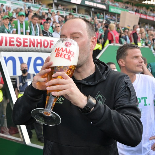 Werder-Trainer Ole Werner trinkt aus einem riesigen Bierglas.