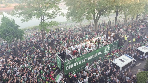 Der Werder-Truck fährt am Osterdeich entlang und die Fans jubeln ihm zu.