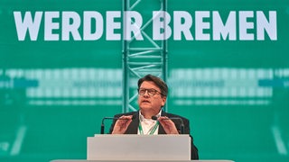 Werder-Präsident Hubertus Hess-Grunewald spricht in zwei Mikrofone.