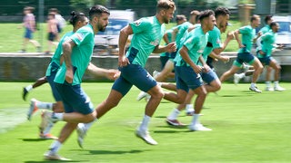 Werder-Spieler sprinten nebeneinander beim Warmmachen während des Trainingslagers.