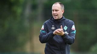 Werder-Trainer Ole Werner klatscht während des Trainings aufmunternd in die Hände.