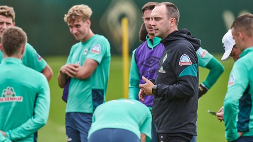 Werder-Coach Ole Werner erklärt seinen Spielern etwas am Rande des Trainings.