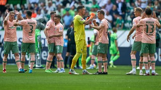 Werder-Spieler klatschen sich nach dem Remis gegen Wolfsburg auf dem Spielfeld ab.