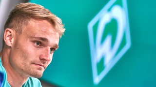 Werder-Verteidiger Amos Pieper bei einer Pressekonferenz in Nahaufnahme.