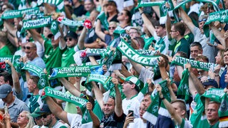 Werder-Fans halten ihre Schals hoch.