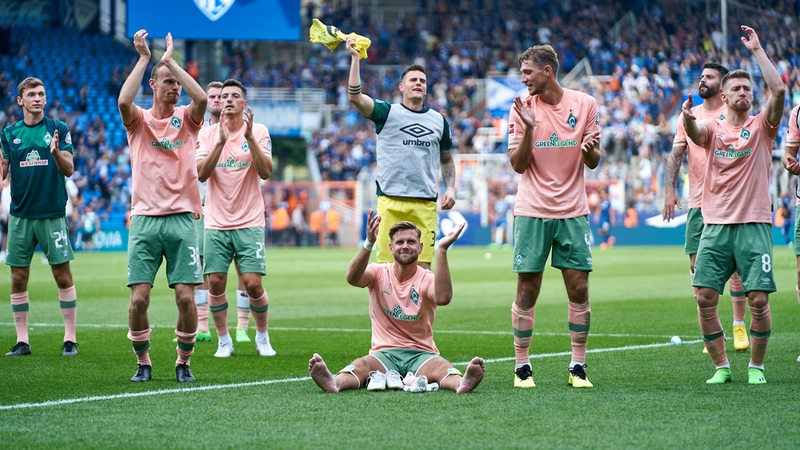 Werder-Spieler stehen im Bochumer Stadion vor ihrem Fanblock und feiern applaudierend den Sieg.
