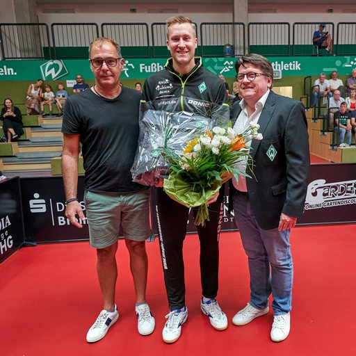 Werders Tischtennis-Profi Mattias Falck wird von Präsident Hubertus Hess-Grunewald für seine Gold- und Bronzemedaille bei der EM mit einem Blumenstrauß und Geschenk geehrt.