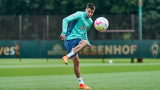 Werder-Profi Ilia Gruev fixiert beim Training den Ball, der auf ihn zugeflogen kommt und bereitet sich auf den Schuss vor.