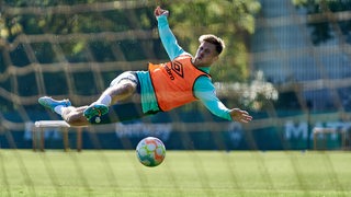 Werder-Stürmer Niclas Füllkrug liegt im Training bei einem Torschuss waagerecht in der Luft.