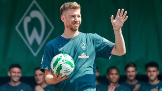 Werder-Profi Mitchell Weiser strahlt bei seinem Auftritt auf der Bühne beim Tag der Fans.