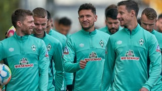 Werder-Spieler um Mitchell Weiser, Marco Friedl und Milos Veljkovic plaudernd auf dem Weg zum Trainingsplatz.