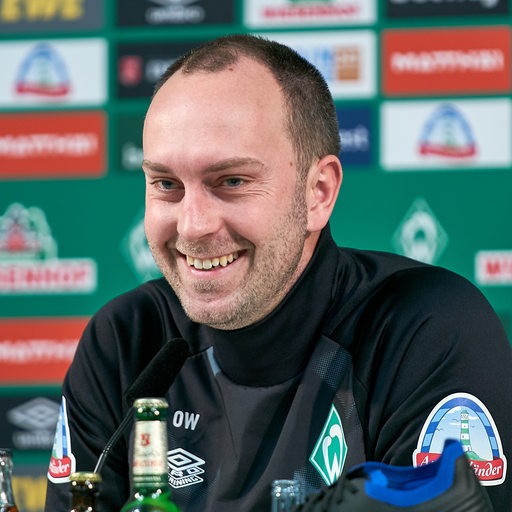 Werder-Trainer Ole Werner lächelt bei der Pressekonferenz.
