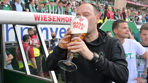 Ole Werner trinkt aus einem sehr großen Bierglas nach dem Aufstieg.