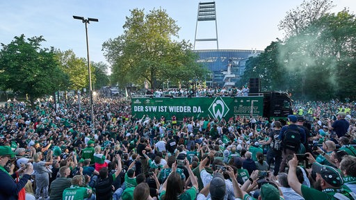 Unzählige Werder-Fans jubeln den auf einem Truck fahrenden Spielern zu.