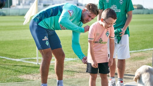 Werder-Spieler Niclas Füllkrug unterschreibt nach der Trainingseinheit in Murcia auf dem Trikot eines kleinen Fans.