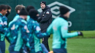 Werder-Trainer Ole Werner blickt zu seinen Spielern auf dem Trainingsplatz.