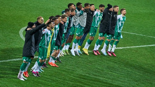 Die Werder-Spieler stehen aufgereiht Arm in Arm vor der Bremer Fankurve und lassen sich feiern.