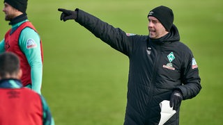 Werder-Coach Ole Werner gibt während des Trainings mit dem ausgestreckten rechten Arm die Richtung vor.