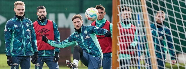 Werder-Spieler stehen beim Training um Niklas Stark herum, der versucht, den Ball ins Tor zu lupfen.