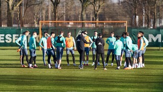 Werder-Spieler stehen am Rande des Trainings im Kreis um Coach Ole Werner herum.