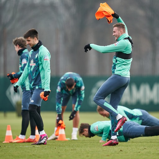 Werder-Spieler Marvin Ducksch springt am Rande des Trainings triumphierend mit einem roten Leibchen in der Hand herum.