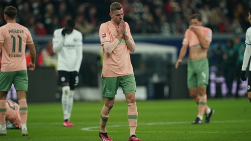 Werder-Stürmer Marvin Ducksch steht nach einem Frankfurter Gegentor enttäuscht auf dem Rasen und hält sich die Hände vors Gesicht.