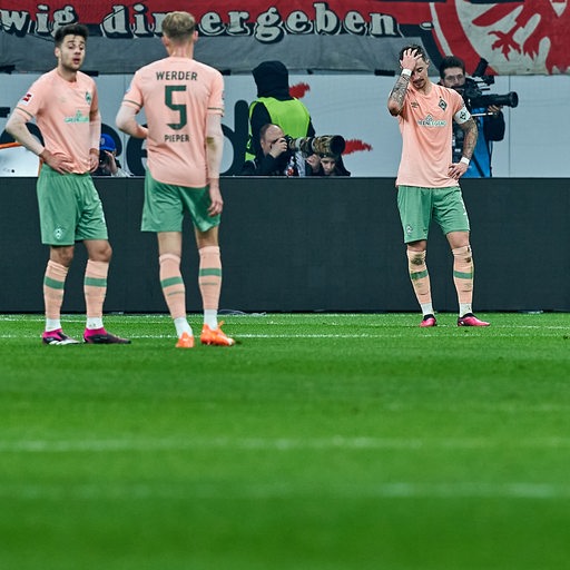 Werder-Spieler um Kapitän Marco Friedl stehen enttäuscht auf dem Rasen.