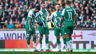 Mehrere Werder-Spieler versammeln sich vor einem Freistoß.