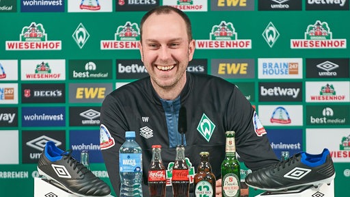 Werder-Trainer Ole Werner lacht während einer Pressekonferenz.