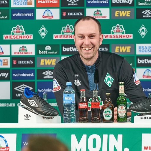Werder-Trainer Ole Werner lacht während einer Pressekonferenz.