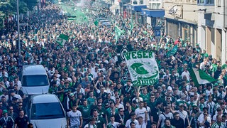 Blick von oben auf den Werder-Fanmarsch durch das Bremer Steintor-Viertel, dicht gedrängt Fans mit Flaggen laufen auf Straßen und Fußwegen.