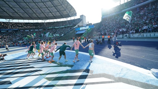Werder-Spieler feiern ausgelassen den Sieg vor der Fankurve im Berliner Olympiastadion.