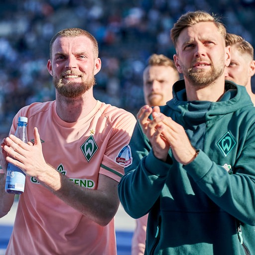 Die Werder-Stürmer Marvin Ducksch und Niclas Füllkrug applaudieren nach dem Sieg in Berlin den mitgereisten Fans.