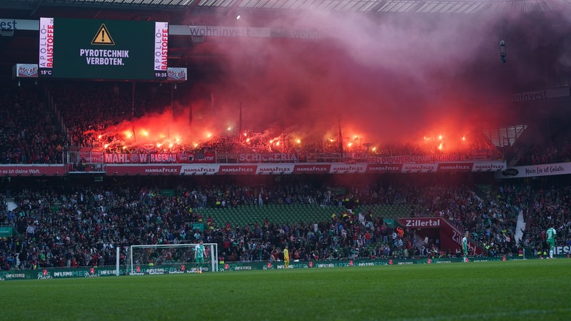 Blick auf den Bayern-Gästeblock im Weser-Stadion, in dem Pyrotechnik abgebrannt wird. Die Tribüne darunter ist teilweise geräumt.