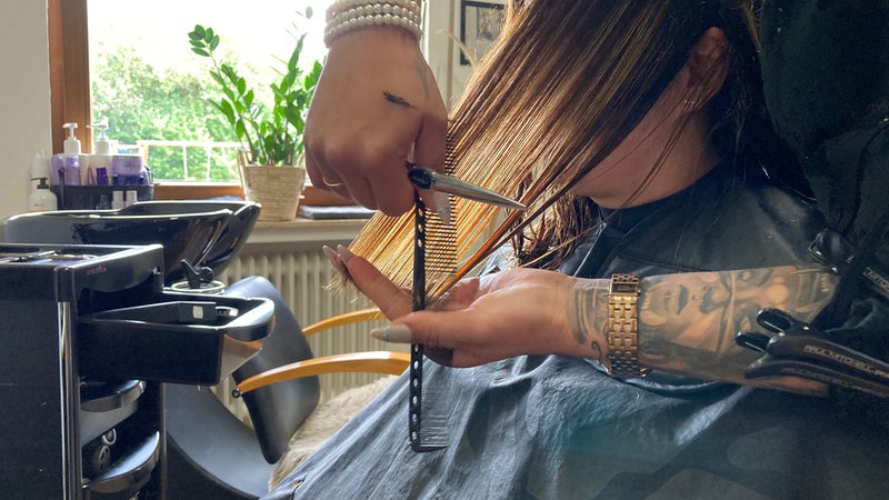 Eine Friseurin schneidet einer Kundin die Haare. 