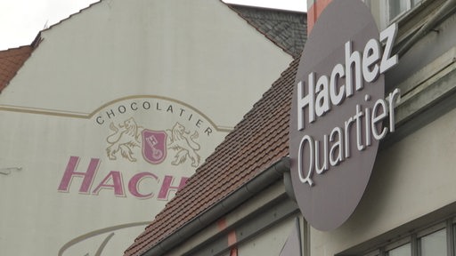 Ein Gebäude von außen und das "Hachez Quartier"-Logo zu sehen.