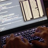 Quellcode eines Webservers sowie die Windows-Eingabeaufforderung sind auf einem Laptop im Dunkeln zu sehen.