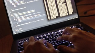  Quellcode eines Webservers sowie die Windows-Eingabeaufforderung sind auf einem Laptop im Dunkeln zu sehen.
