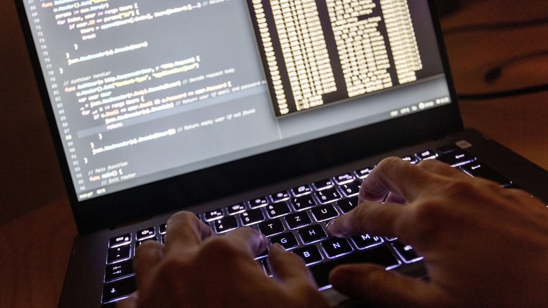  Quellcode eines Webservers sowie die Windows-Eingabeaufforderung sind auf einem Laptop im Dunkeln zu sehen.