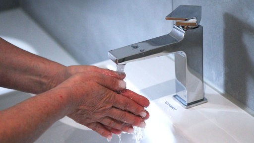 Ein Mensch wascht seine Hände im Bad